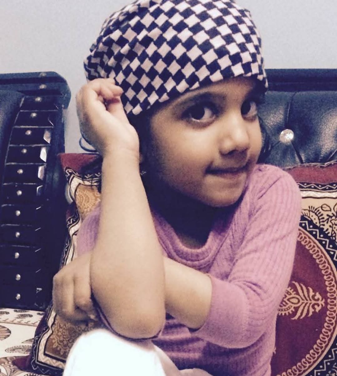 A cheerful child wearing a plum top and patterned bonnet